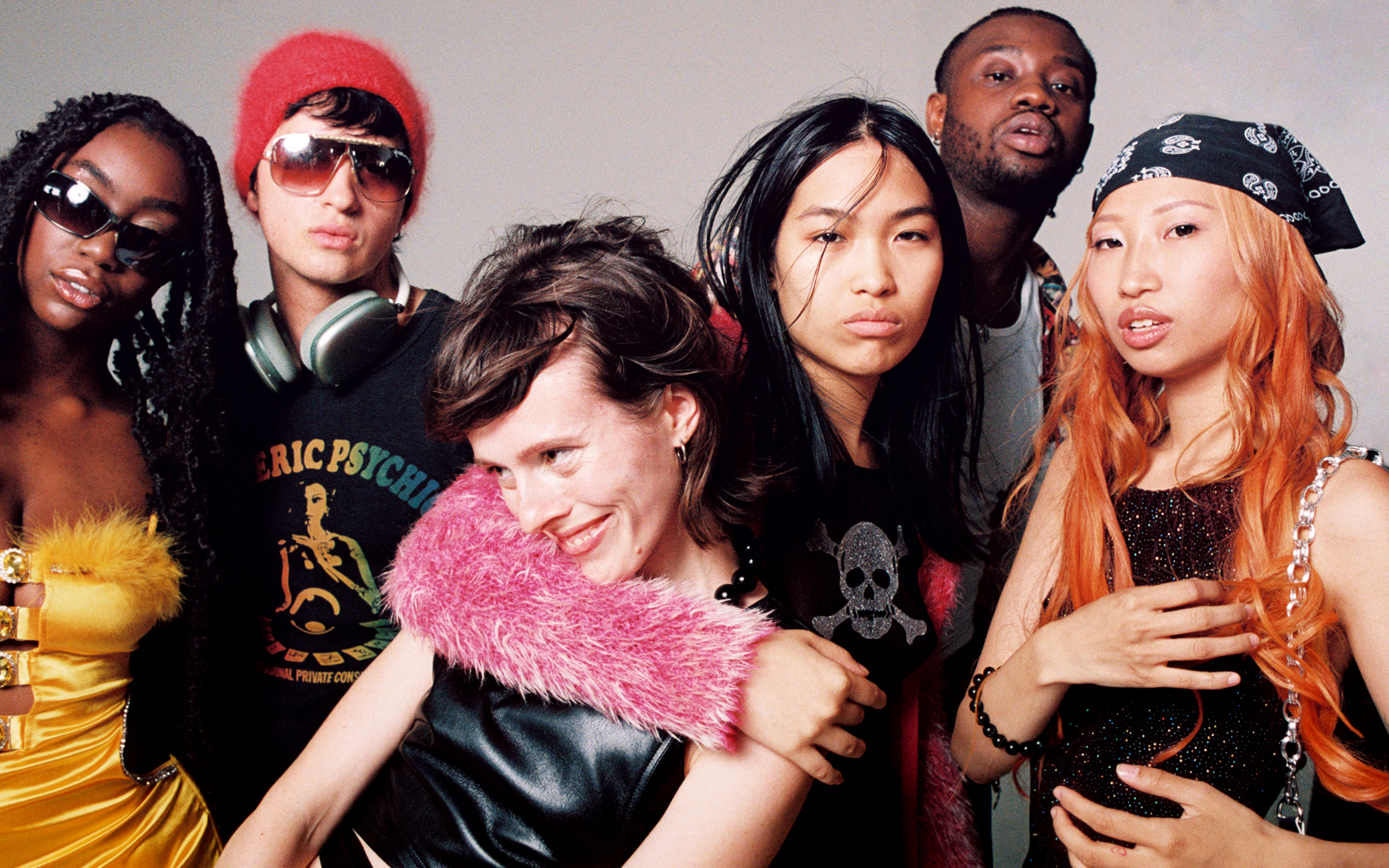 A diverse group of six individuals pose with confidence in distinct and stylish outfits against a grey backdrop for an 'Office Magazine' photoshoot.